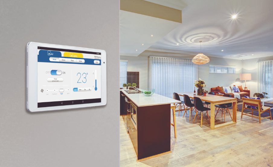 MyAir wall-mounted touchscreen controller beside an open-plan living area